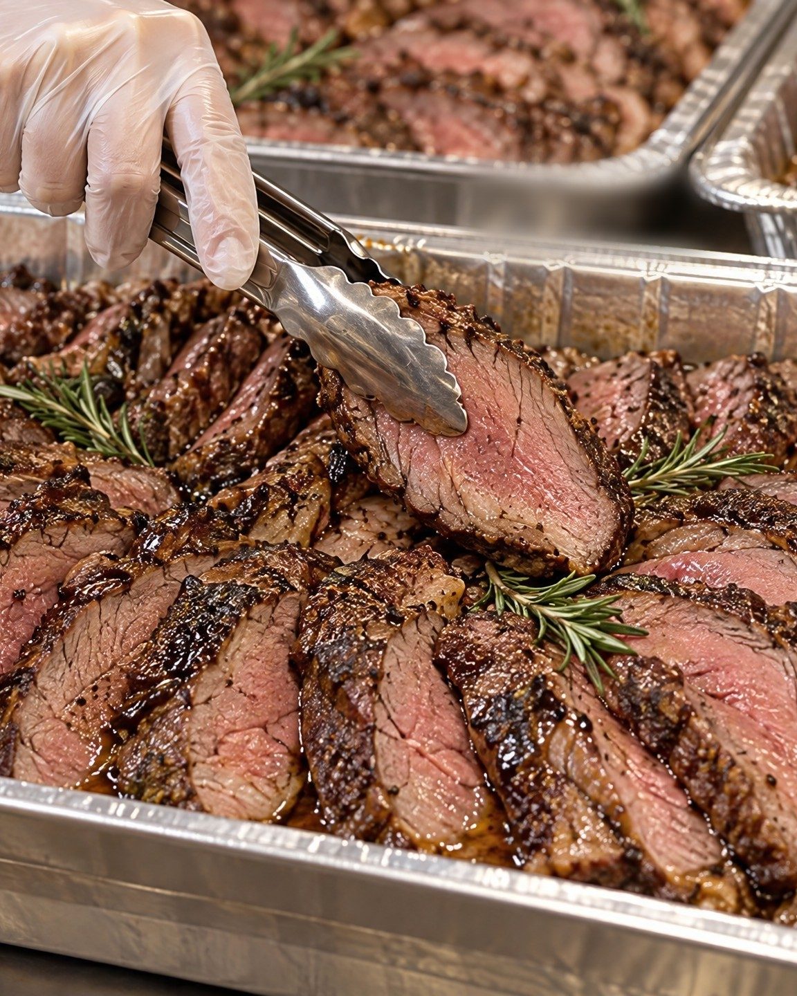 Sliced roast beef steak in a foil pan, ready for the Ladies Bikur Cholim meal trays
